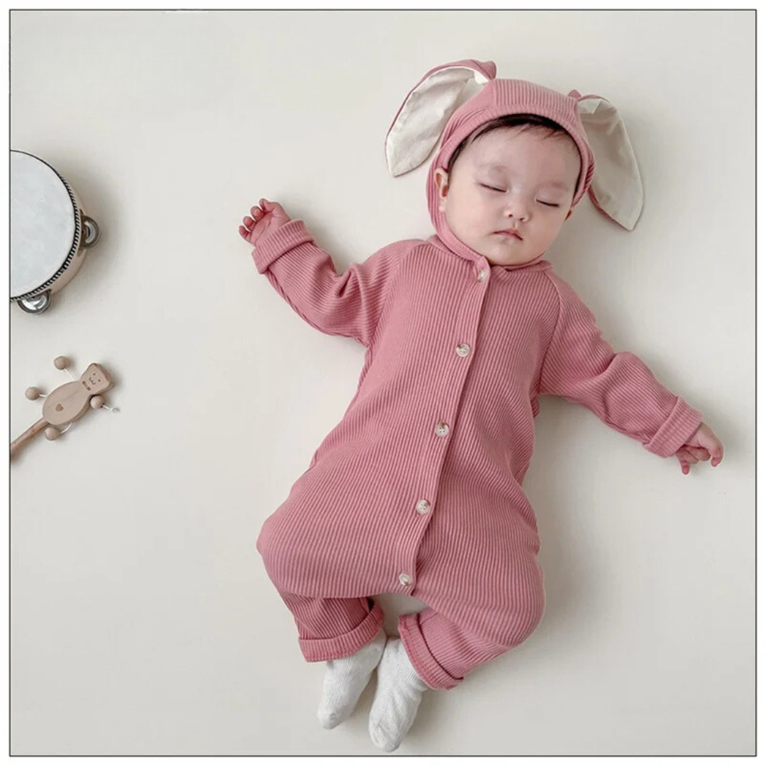 Pink hooded baby romper shown on a baby, with long bunny ears and front buttons