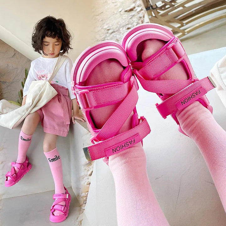 Pink sandals with crisscross straps shown close up on feet and with a child&
