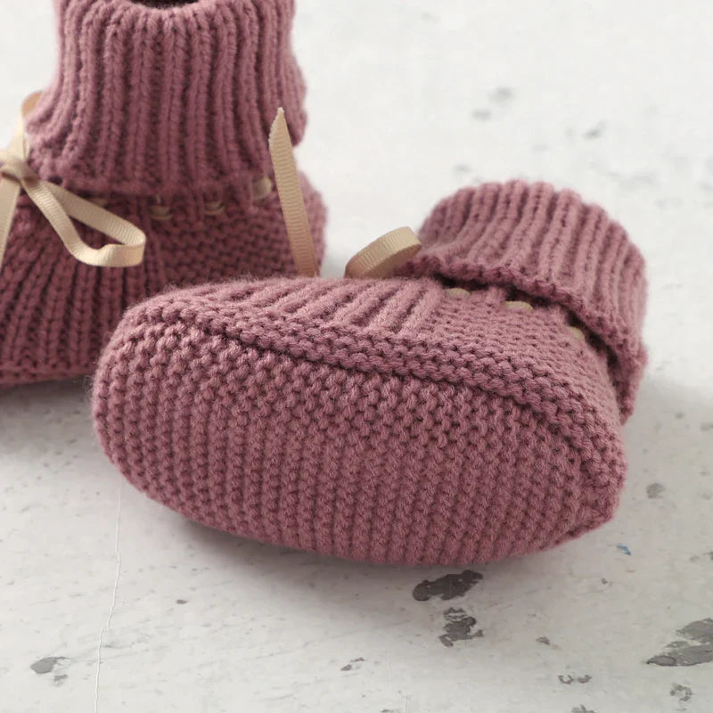 Pink knitted baby bootie showing the sole and rounded toe