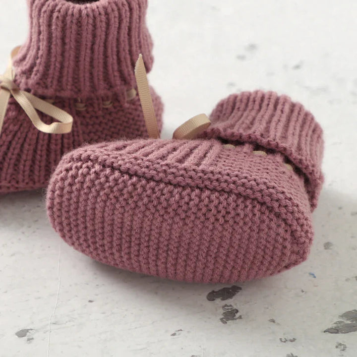 Pink knitted baby bootie showing the sole and rounded toe