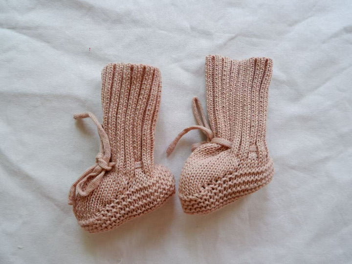 Pink knitted baby booties with tall ribbed cuffs and matching ankle ties.