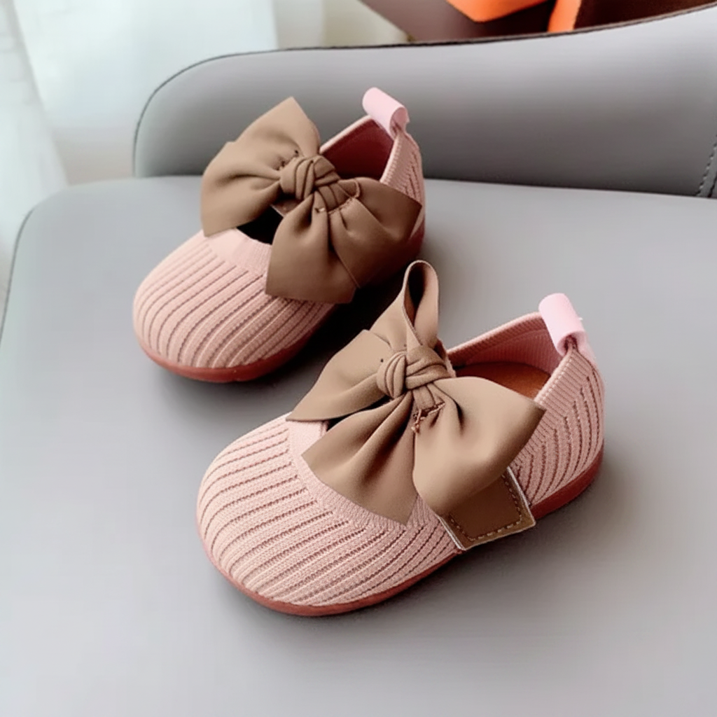 Pink knitted baby shoes with brown bows and matching pink soles