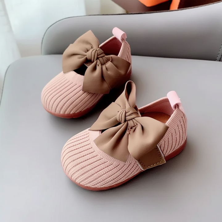 Pink knitted baby shoes with brown bows and matching pink soles