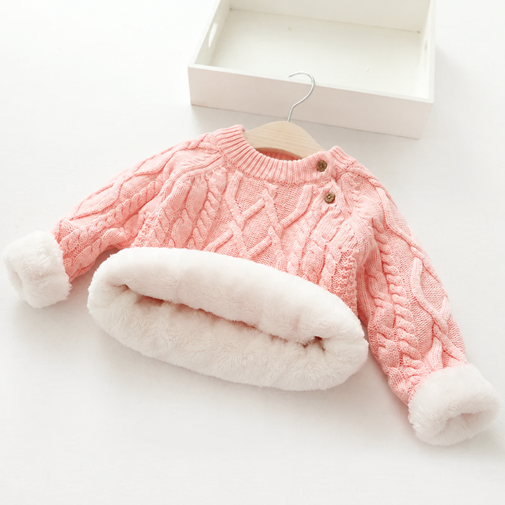 Pink cable-knit sweater with turned-back cuffs and hem showing plush white lining.