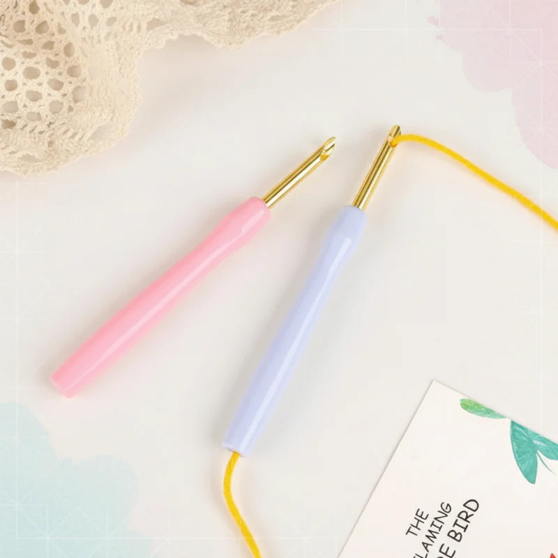 Pink and lavender punch needles, with yellow yarn threaded through one needle