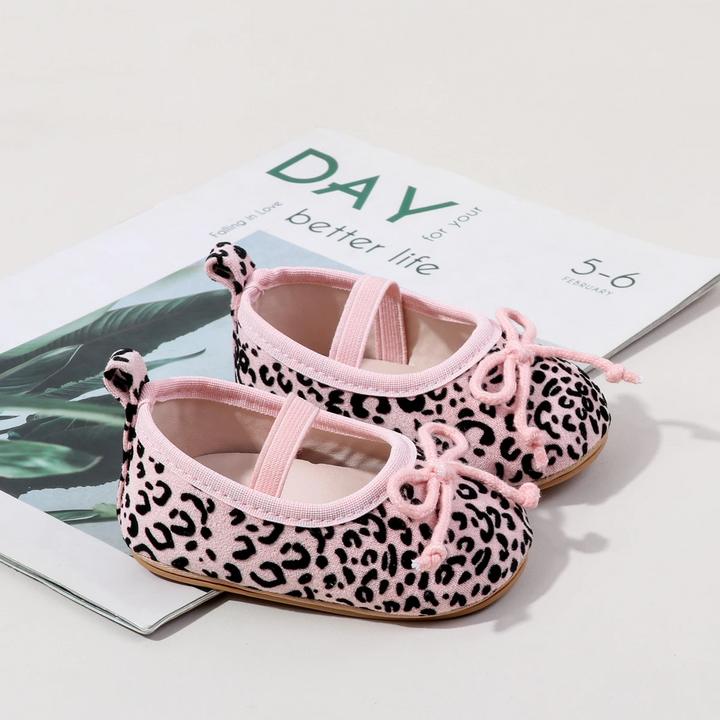 Pair of pink leopard-print baby shoes with pink elastic straps and toe bows