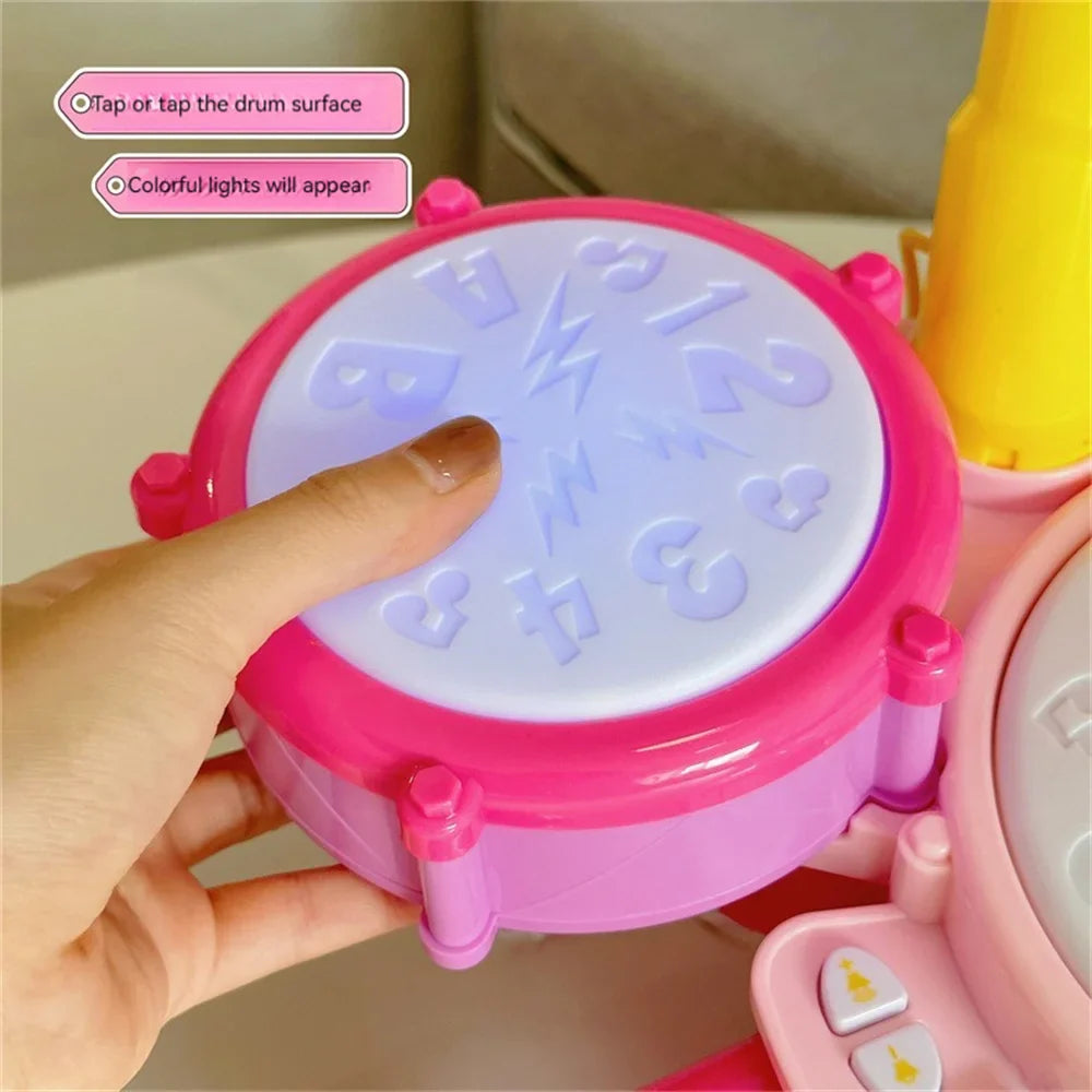 A finger tapping an illuminated drum pad on the pink toy drum set
