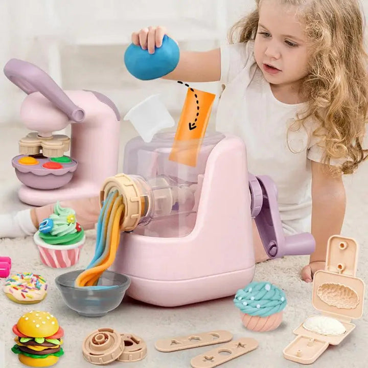 Child holding blue clay beside a pink hand-crank pasta maker and pretend food creations