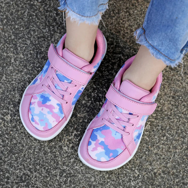 Overhead view of pink camouflage sneakers worn with cropped jeans on pavement