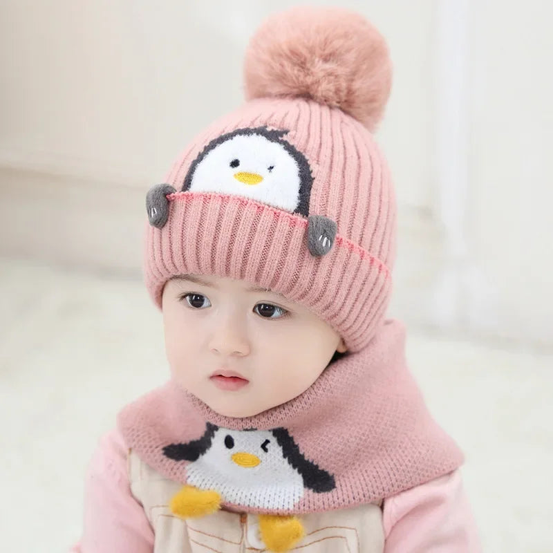 Child wearing a pink penguin pom-pom hat with a matching scarf