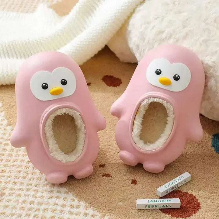 Pink penguin slippers with cream-colored lining on a patterned rug