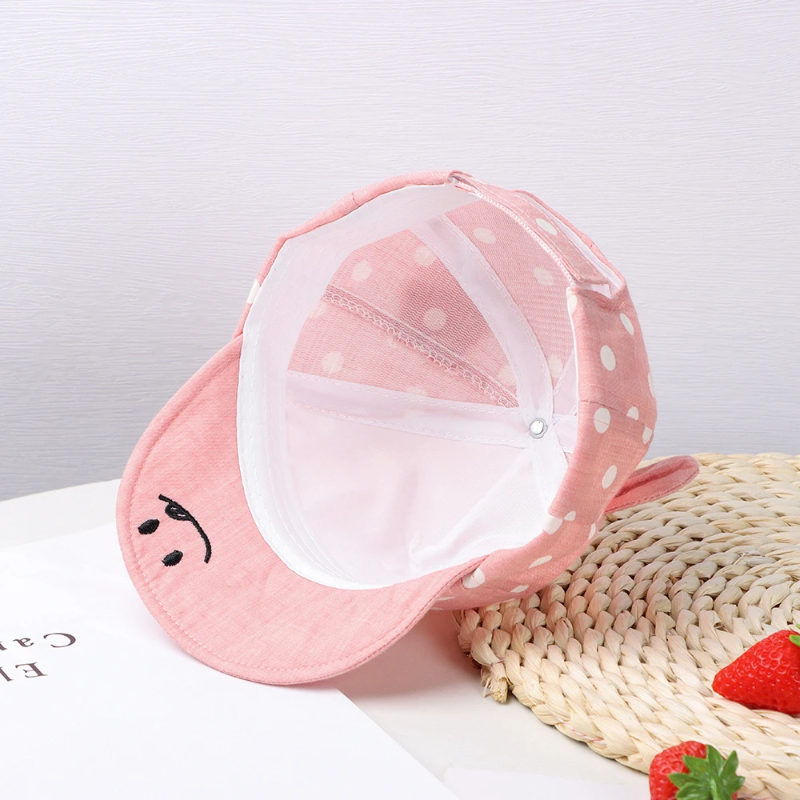 Inside view of a pink polka dot cap showing the inner seams and curved brim.