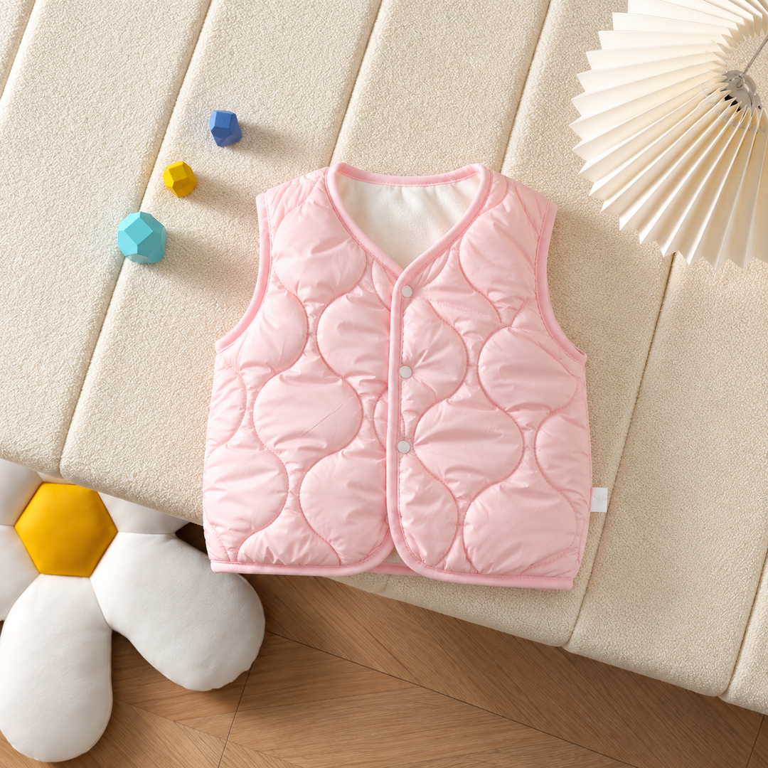 Pink quilted baby vest with front snaps laid on a cream cushion.