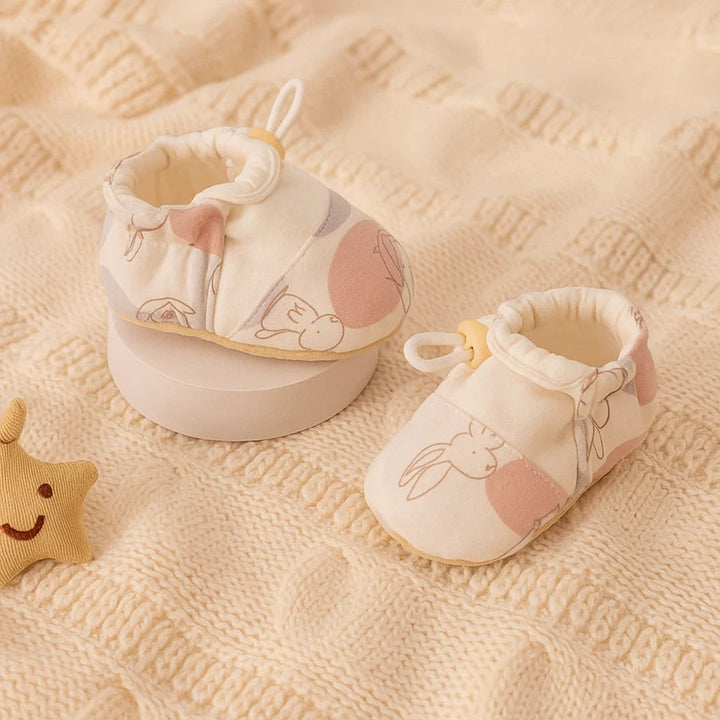 Pink-and-white baby shoes with rabbit outlines and gathered ankle openings