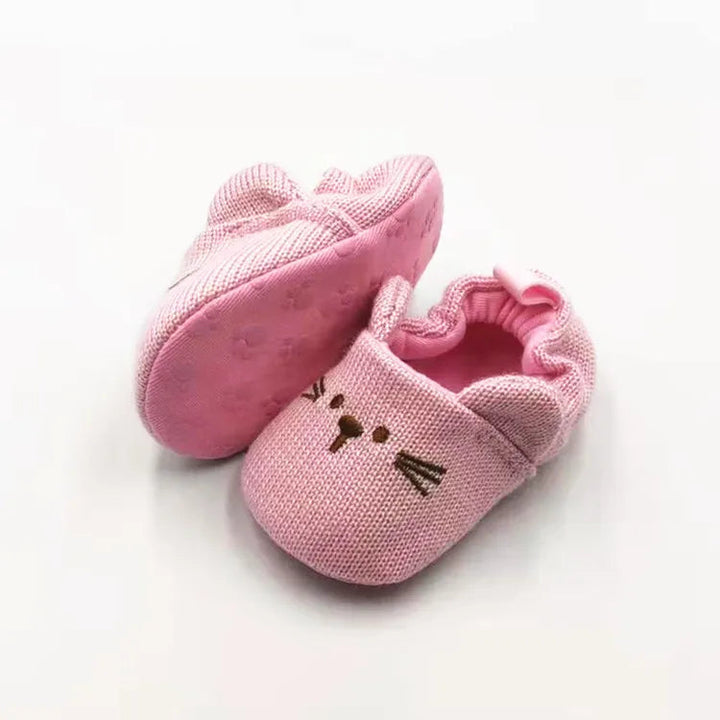 Pink rabbit baby slippers with embroidered faces and one sole turned upward