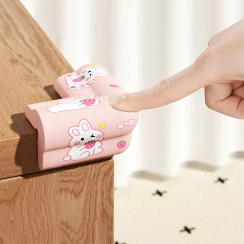 A finger presses the top of a pink rabbit-print foam cover on a wooden corner.