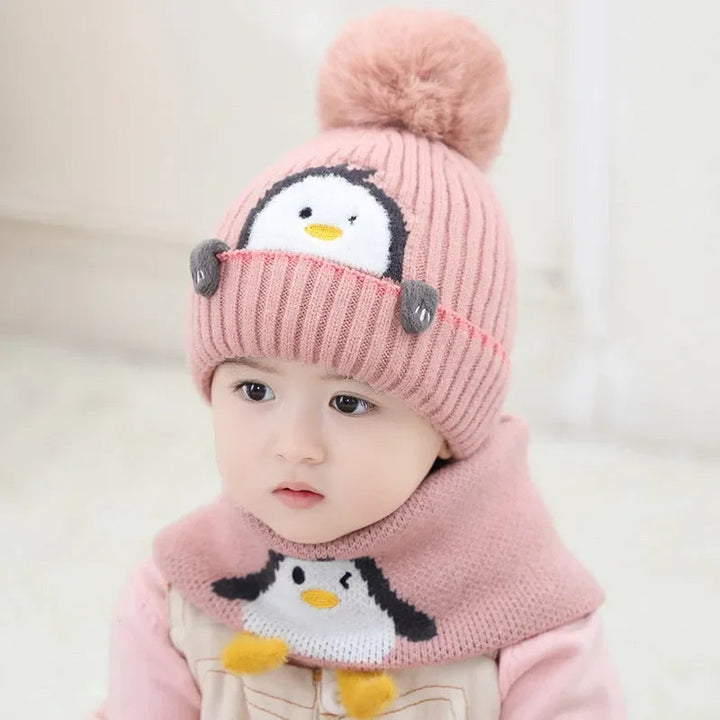 Front view of a child wearing a pink ribbed penguin hat and coordinating scarf