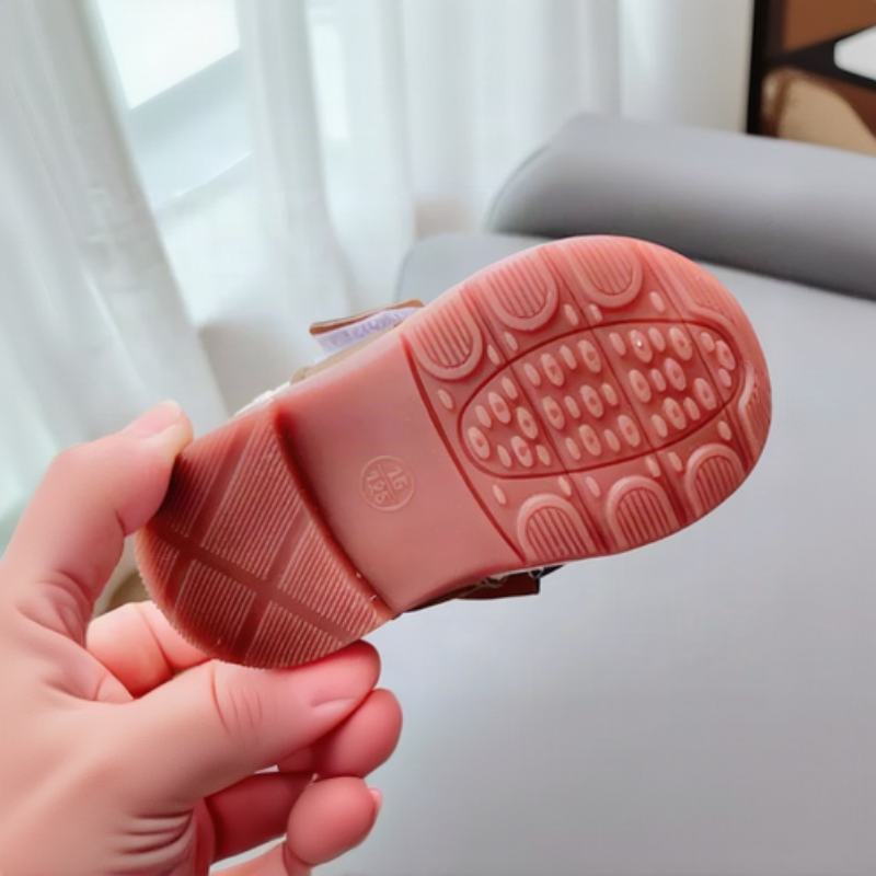 Underside of a baby shoe showing its patterned pink rubber outsole