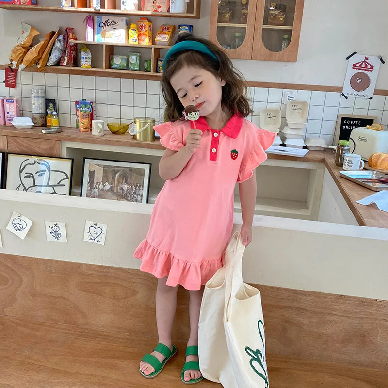 Full-length view of a child wearing the pink strawberry dress with ruffled sleeves and hem