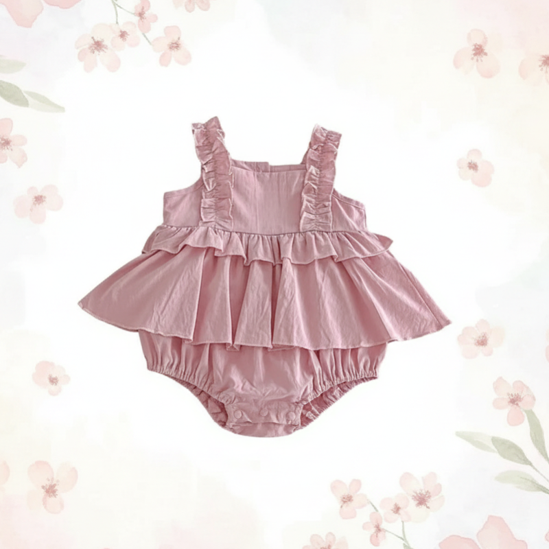 Pink ruffle baby dress romper with a square neckline, displayed on a floral backdrop