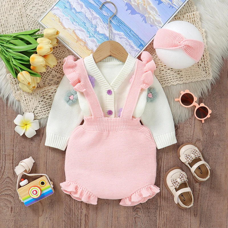 Pink ruffled overalls layered over a white floral cardigan with a matching knit headband