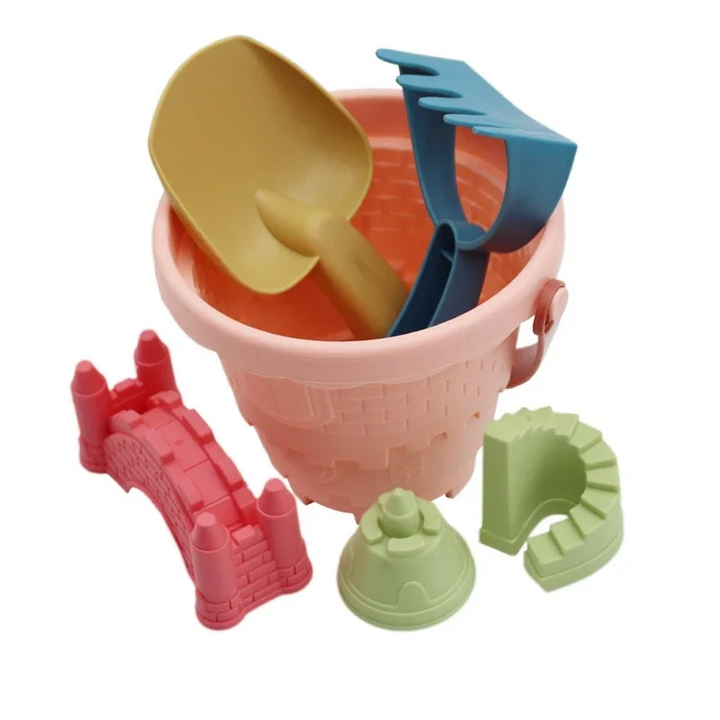 Pink sandcastle bucket with a yellow scoop, blue rake, and three sand molds