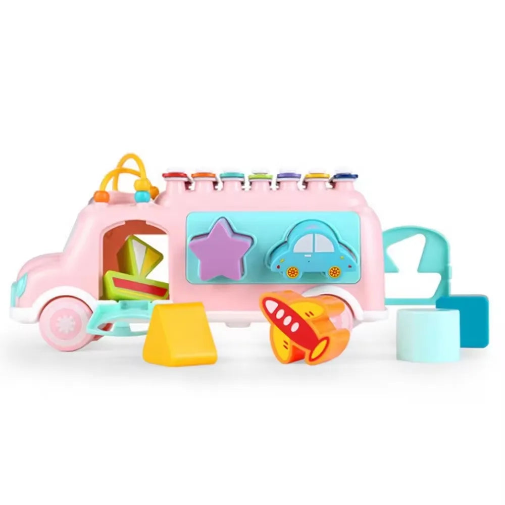 Pink musical toy bus with shape-sorting windows, an open rear door, and colorful blocks