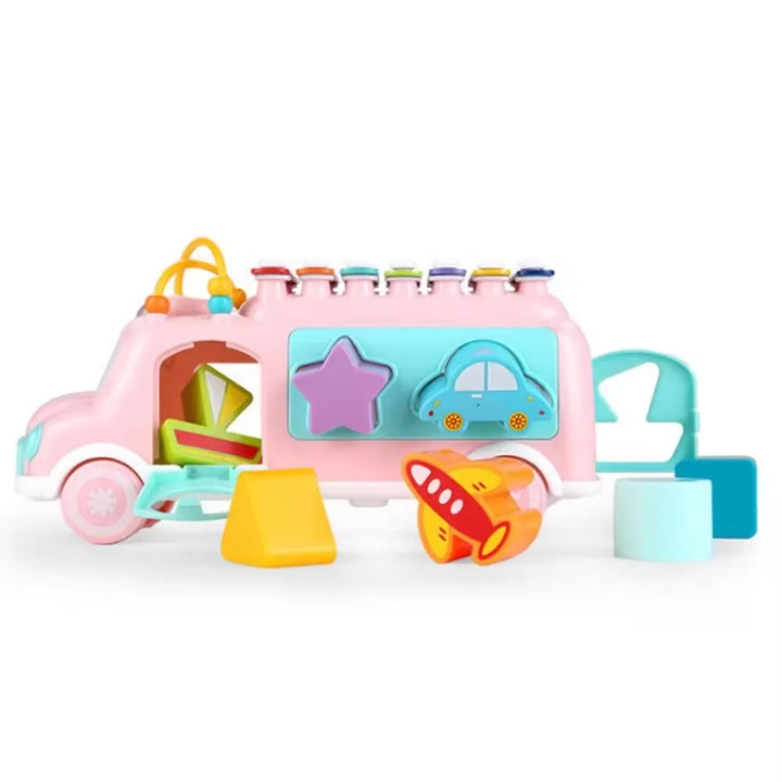 Pink musical toy bus with shape-sorting windows, an open rear door, and colorful blocks