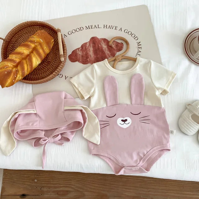 Pink short-sleeve cotton bunny bodysuit beside its matching cap