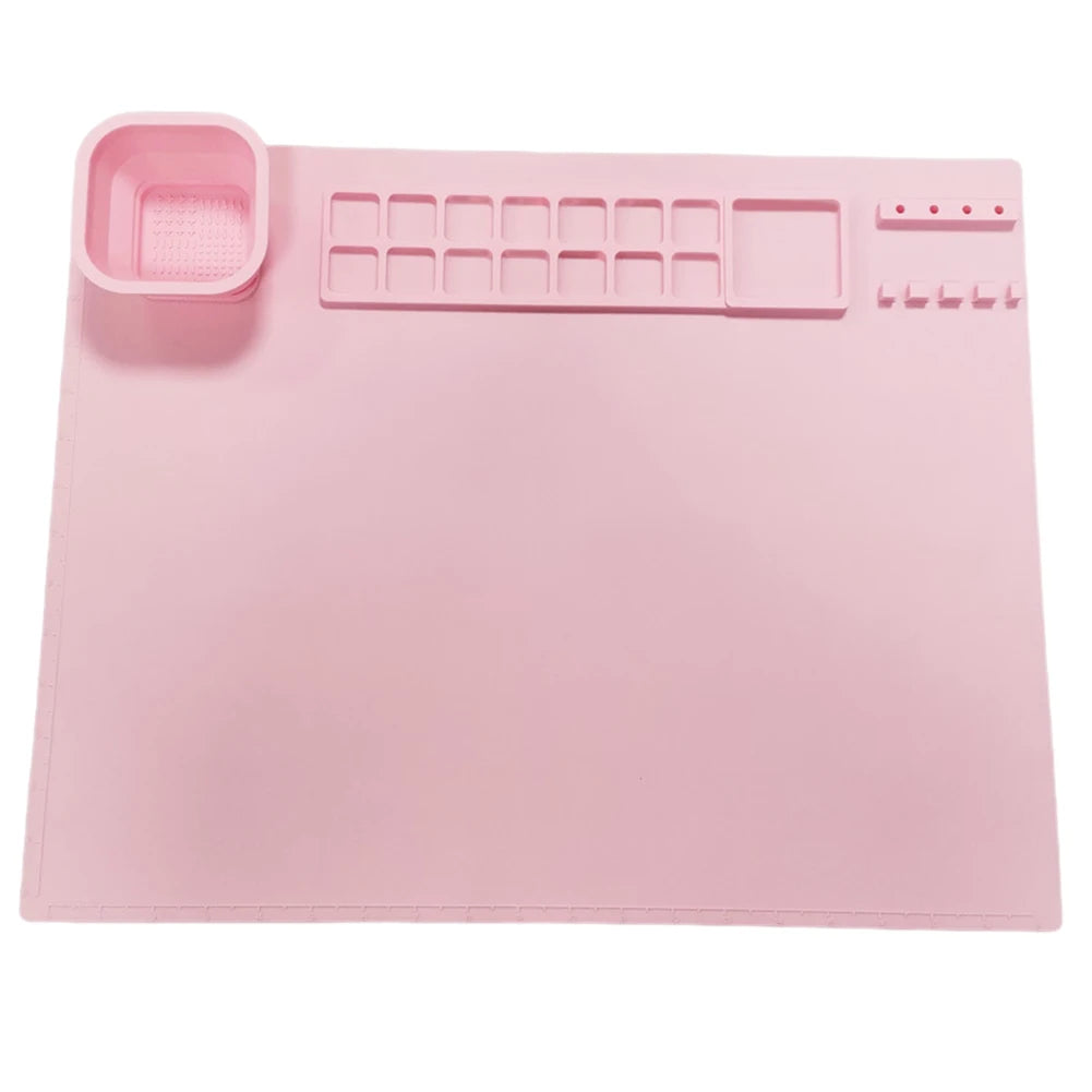 Pink silicone craft mat with a cup, paint wells, mixing area, and brush holders.