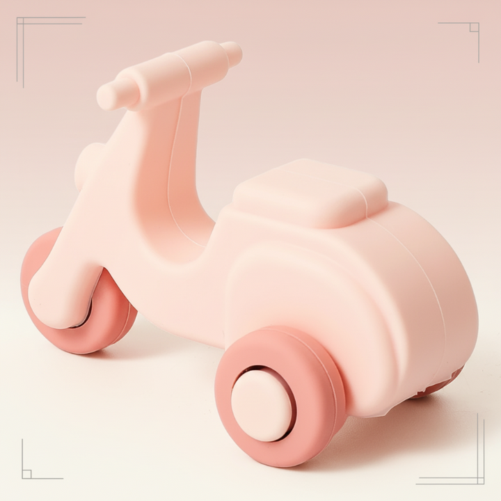Pink silicone scooter teether with rounded wheels and an open center
