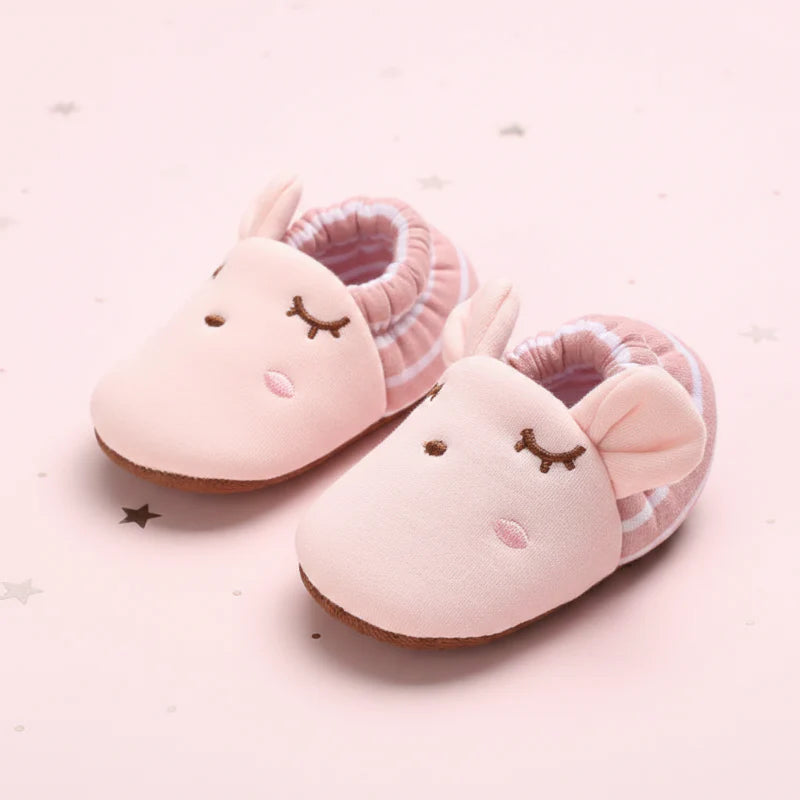 Pink baby shoes with embroidered sleepy faces and striped elastic cuffs.