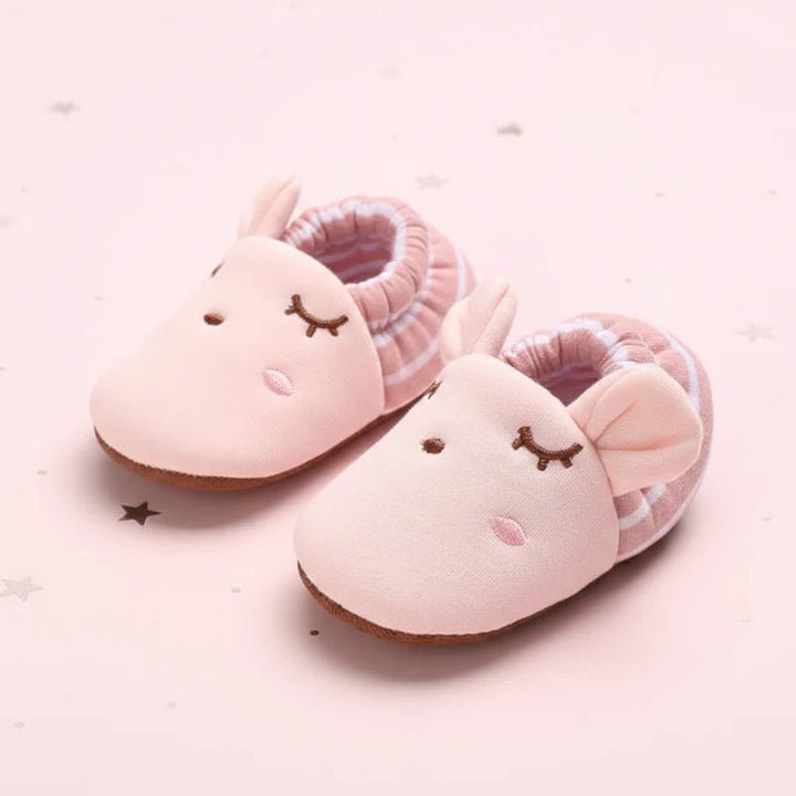 Pink baby shoes with embroidered sleepy faces and striped elastic cuffs.