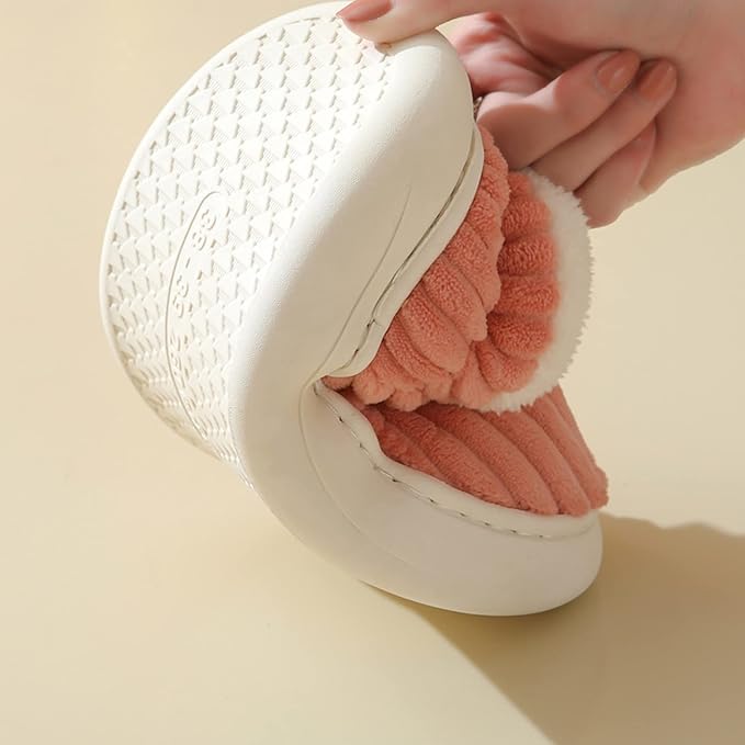 Pink slipper bent by hand to show its flexible white sole and textured tread.