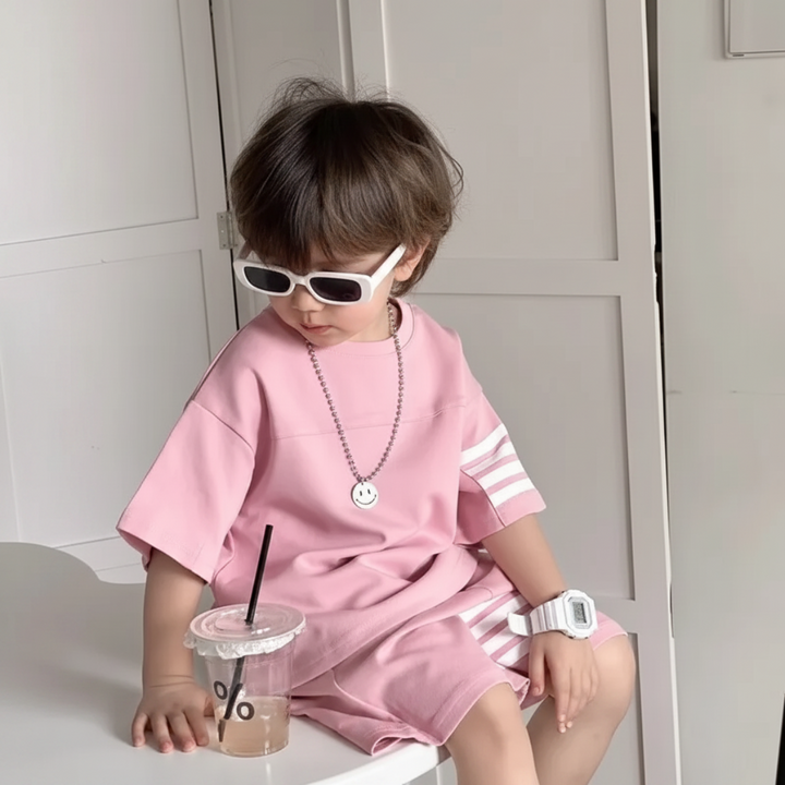 Child seated in the pink T-shirt and matching shorts with white stripe details.