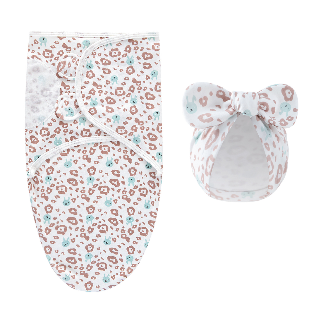 White swaddle blanket and matching bow hat with small pink and teal markings