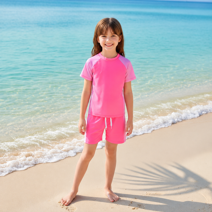 Child standing by the ocean in a pink two-piece swimsuit