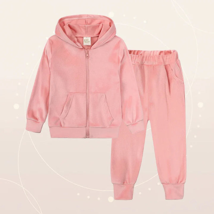 Pink velvet zip-up hoodie and matching cuffed pants on a beige backdrop