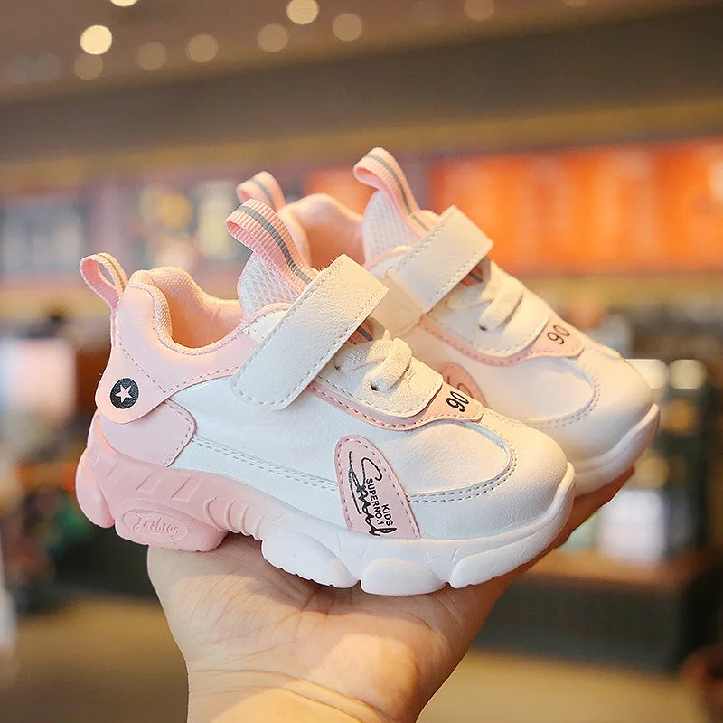 Pair of white kids' sneakers with pink accents, wide straps, and heel pull tabs