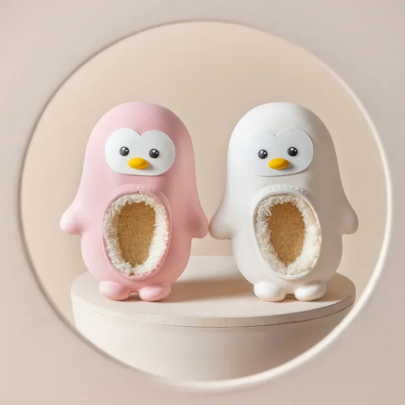 Pink and white penguin slippers with soft-lined openings on a round shelf