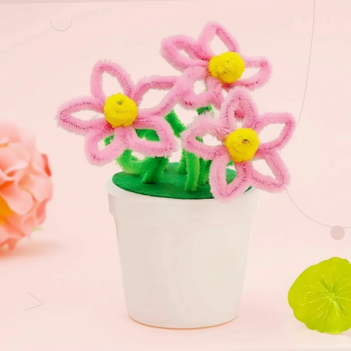 Pink loop-petal flowers with yellow centers and green stems in a white pot