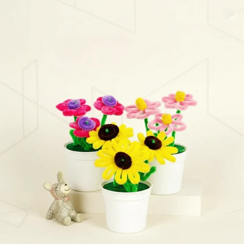 Pink flowers and yellow sunflowers made from fuzzy wire, displayed in white pots