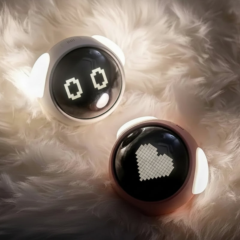 White and pink alarm clocks showing pixel eyes and a heart on a fluffy surface
