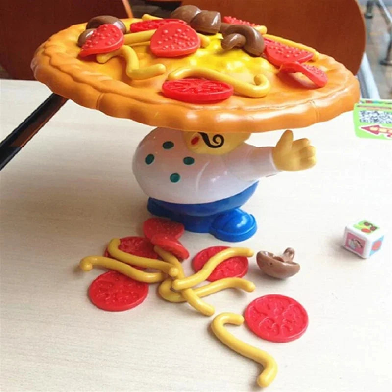 Pizza balancing game on a table with loose toppings and a die beside the chef base