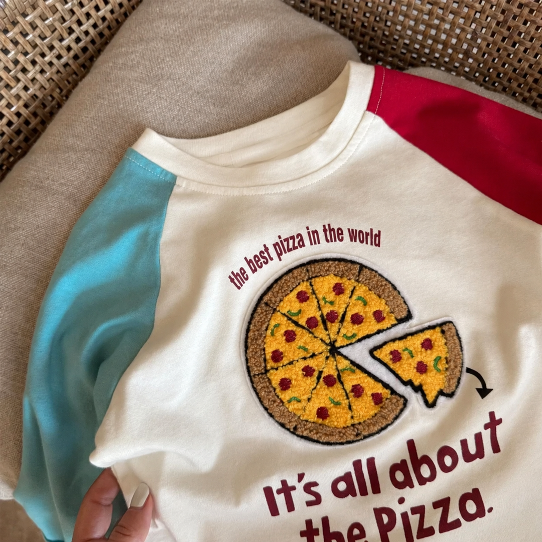 Close-up of a pizza graphic on a cream shirt with teal and red raglan sleeves