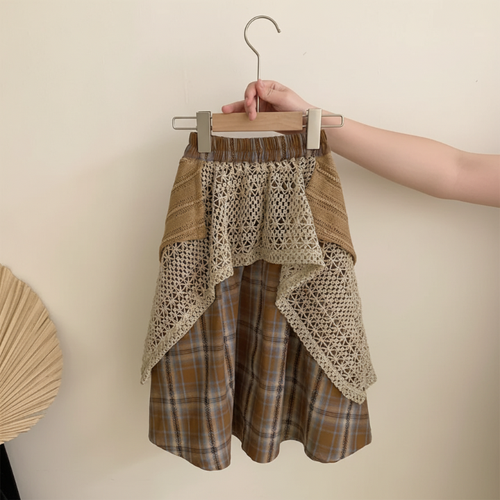 Brown plaid skirt with layered crochet panels and solid fabric accents held on a hanger