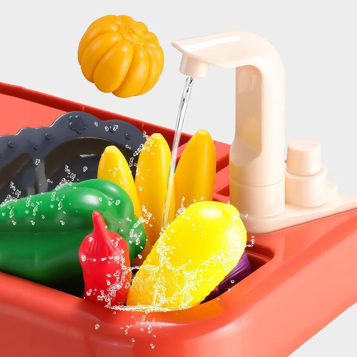 Water flowing from the toy kitchen faucet over colorful play vegetables in the sink.