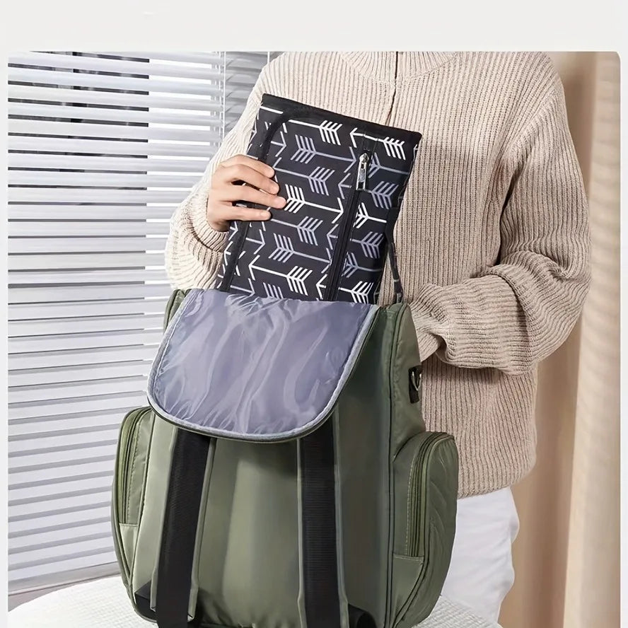 Folded arrow-print changing mat held above an open backpack.