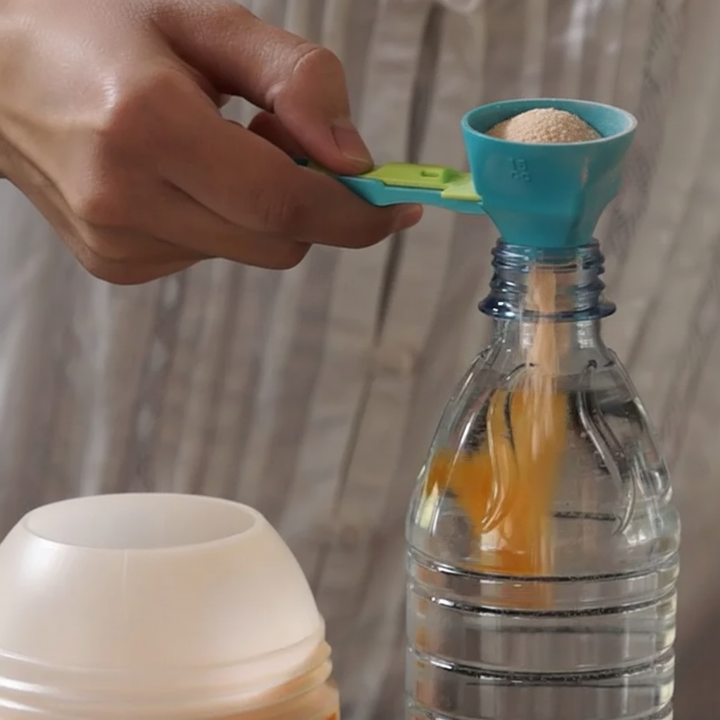 Measuring scoop holding powder over a narrow bottle opening