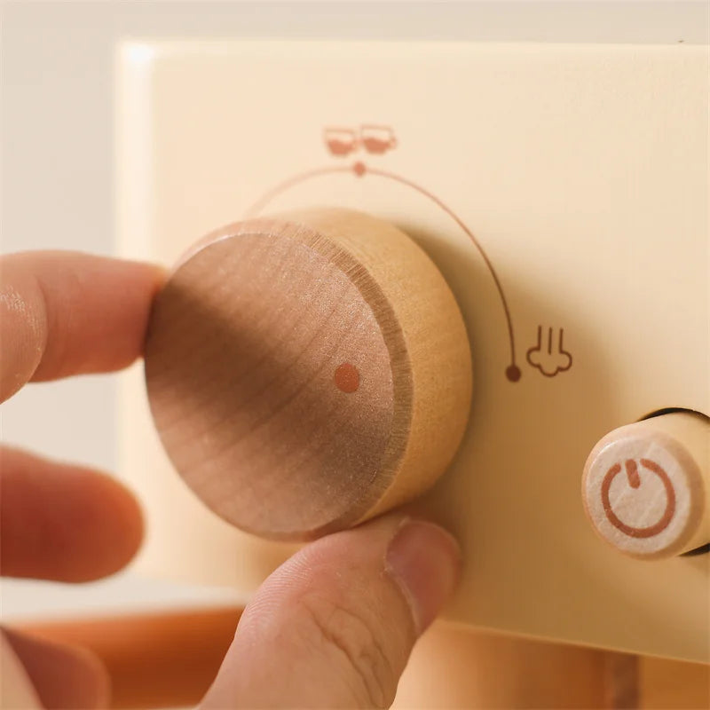 Hand turning the large wooden dial on the toy coffee machine.